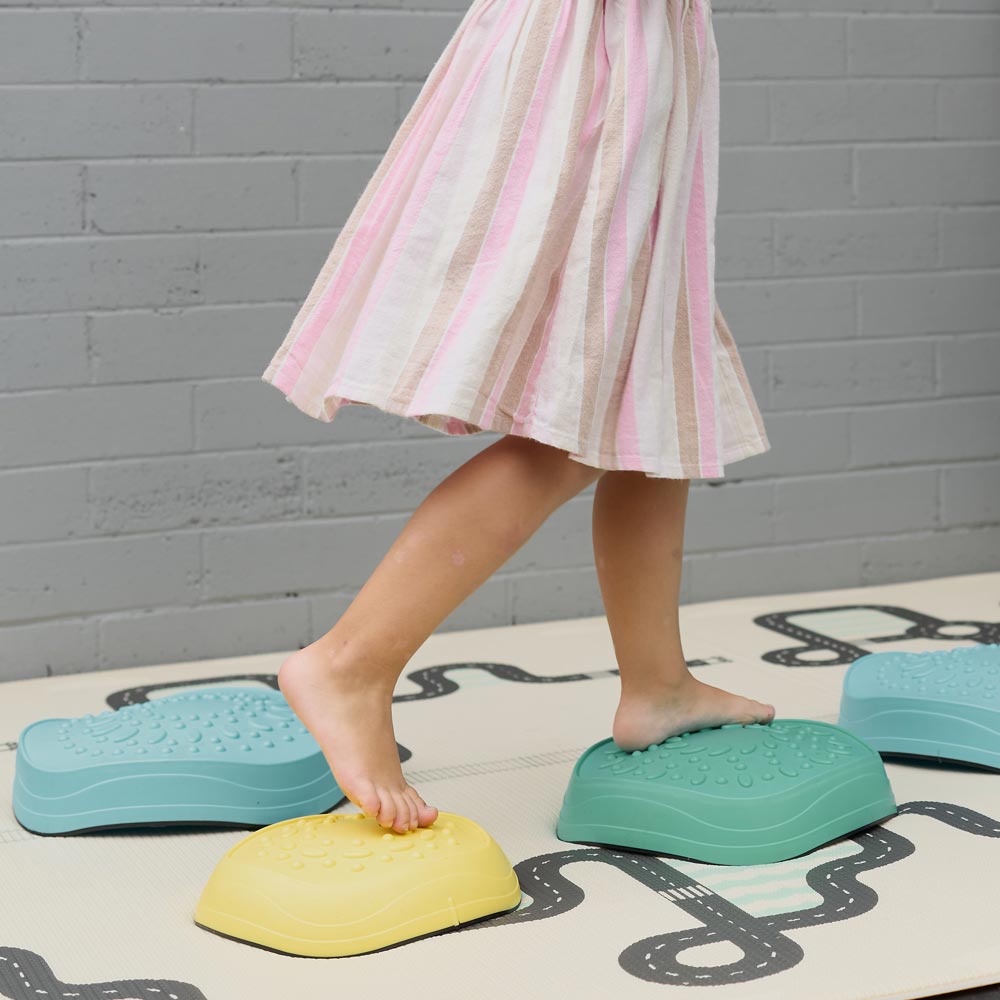 Young female child playing on colourful stepping stones.